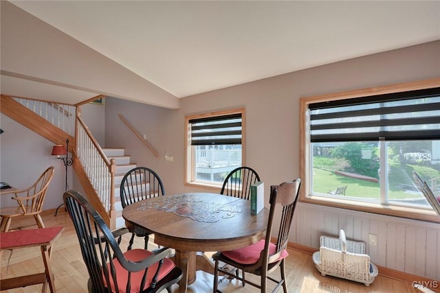21157 Home St, Alexandria, NY 13607 - dining space featuring light wood-style floors, stairs, vaulted ceiling, wooden walls, and a wainscoted wall