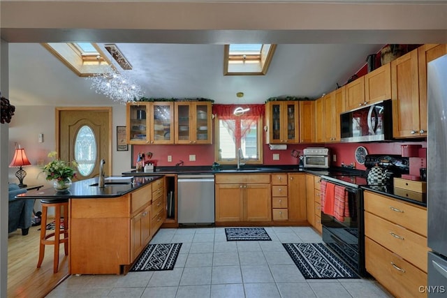 21157 Home St, Alexandria, NY 13607 - kitchen with stainless steel appliances, a skylight, dark countertops, glass insert cabinets, and a kitchen bar