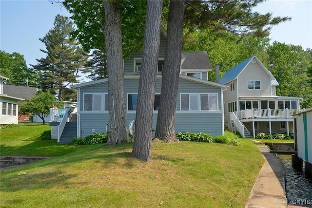 21157 Home St, Alexandria, NY 13607 - back of property with stairs, a sunroom, a lawn, and a deck