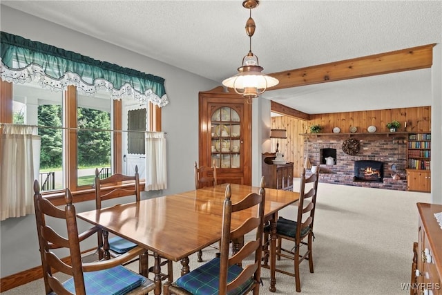 10400 Springville Boston Rd, Concord, NY 14141 - carpeted dining area with wood walls, a brick fireplace, a textured ceiling, and beamed ceiling