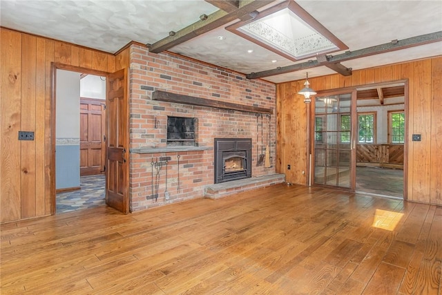 285 Panorama, Penfield, NY 14625 - unfurnished living room with wooden walls, wood-type flooring, beam ceiling, a brick fireplace, and a skylight