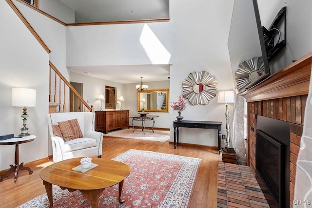 5810 Nobleton Cir, Onondaga, NY 13078 - living room featuring a towering ceiling, light wood-style floors, a chandelier, stairway, and a brick fireplace