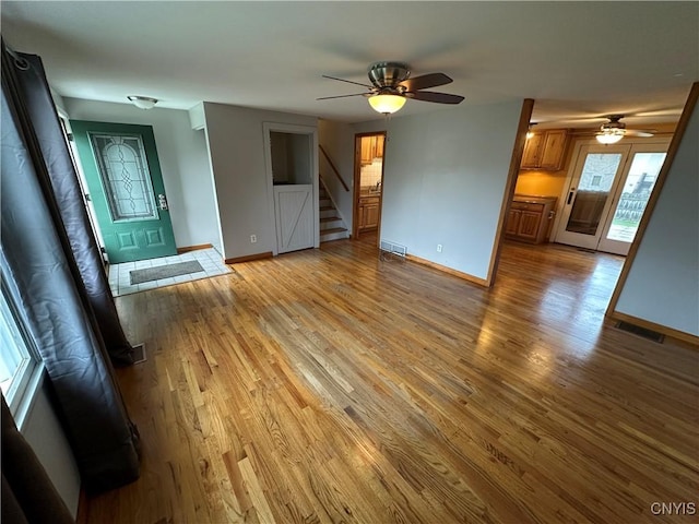 8071 Evesborough Dr, Clay, NY 13041 - unfurnished living room with a ceiling fan, light wood finished floors, and stairs