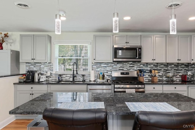 13 Berrywood Rd, Clay, NY 13090 - kitchen featuring appliances with stainless steel finishes, a kitchen bar, tasteful backsplash, and hanging light fixtures