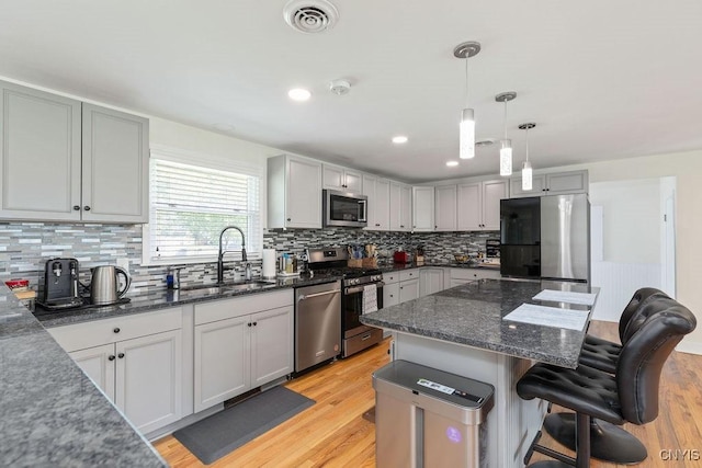 13 Berrywood Rd, Clay, NY 13090 - kitchen featuring appliances with stainless steel finishes, a kitchen breakfast bar, light wood finished floors, tasteful backsplash, and dark stone countertops