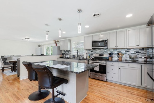 13 Berrywood Rd, Clay, NY 13090 - kitchen featuring stainless steel appliances, a breakfast bar area, decorative backsplash, hanging light fixtures, and a kitchen island