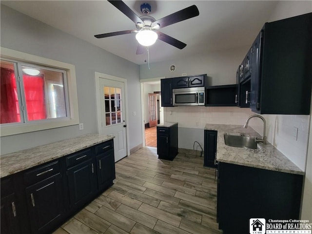116 Park St, Jamestown, NY 14701 - kitchen featuring stainless steel microwave, dark cabinetry, backsplash, ceiling fan, and light wood-style floors