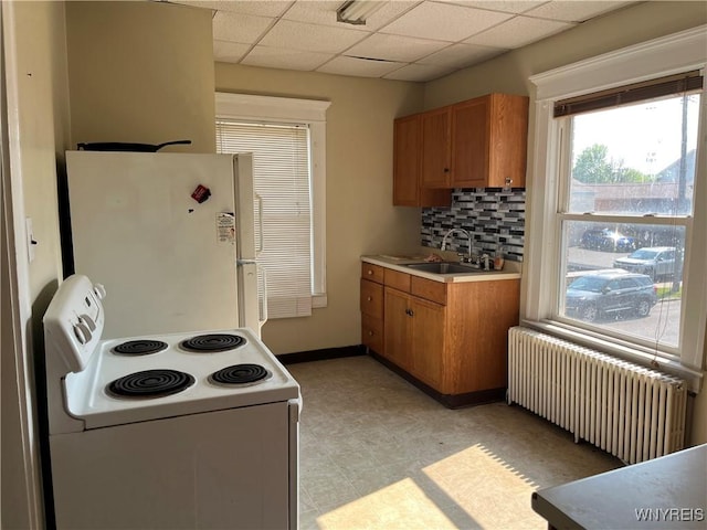 600 Cayuga Dr, Niagara Falls, NY 14304 - kitchen featuring white appliances, radiator, brown cabinetry, a paneled ceiling, and light countertops