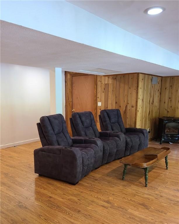 1324 New Seabury Ln, Victor, NY 14564 - living room with light wood finished floors, a wood stove, and wood walls