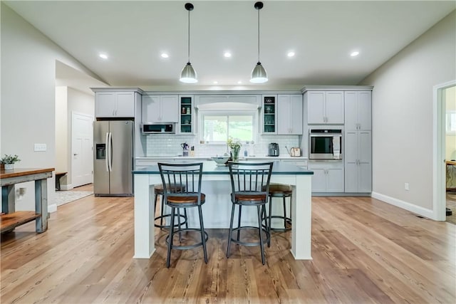 4338 State Route 90, Springport, NY 13160 - kitchen featuring stainless steel appliances, a kitchen island, decorative backsplash, a kitchen bar, and decorative light fixtures