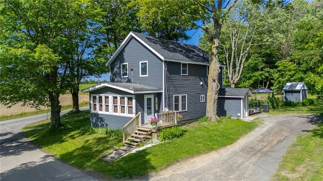 3839 Thompson Ave, Castile, NY 14549 - view of front facade featuring driveway, roof with shingles, a storage unit, and a front yard