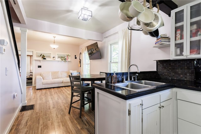 3839 Thompson Ave, Castile, NY 14549 - kitchen with light wood-style flooring, white cabinetry, glass insert cabinets, and decorative backsplash