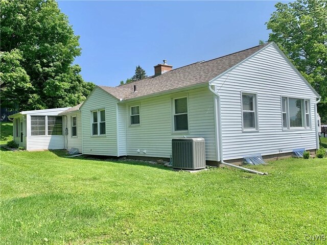 17 Benton Cir, New Hartford, NY 13501 - back of property featuring a chimney, a yard, roof with shingles, and a sunroom