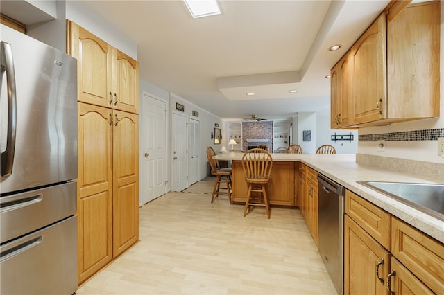 208 Blackwell Ln, Henrietta, NY 14467 - kitchen with stainless steel appliances, a peninsula, light countertops, a breakfast bar, and light wood-type flooring