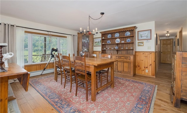 377 Bingham Center Rd, Bingham, PA 16923 - dining space featuring baseboard heating, a chandelier, light wood-style floors, a wainscoted wall, and wooden walls