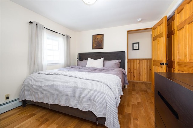 377 Bingham Center Rd, Bingham, PA 16923 - bedroom with light wood-style flooring, wainscoting, a baseboard radiator, and wooden walls