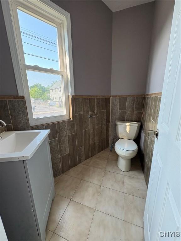 918 Shaw St, Utica, NY 13502 - half bath featuring tile walls, tile patterned floors, vanity, and wainscoting