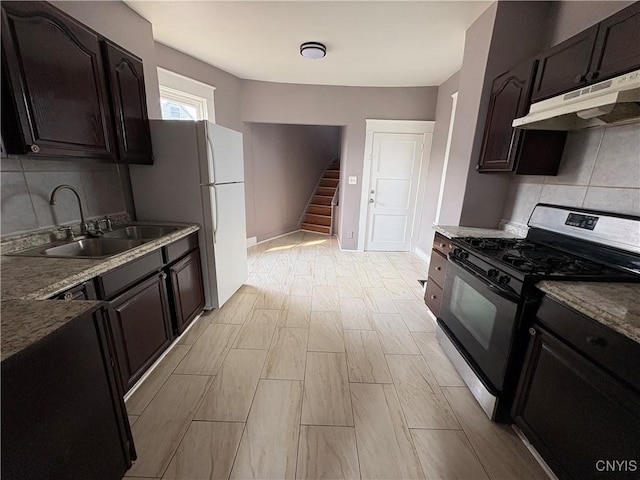 918 Shaw St, Utica, NY 13502 - kitchen with gas stove, under cabinet range hood, tasteful backsplash, and freestanding refrigerator