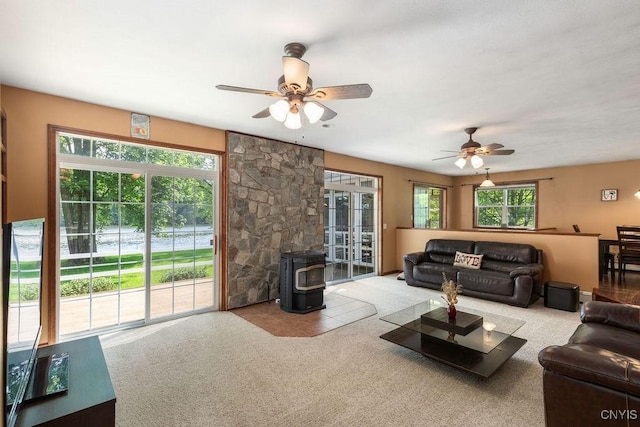 98 Krystyna Ln Unit 6, Cato, NY 13080 - living room featuring a wood stove, ceiling fan, carpet flooring, and healthy amount of natural light