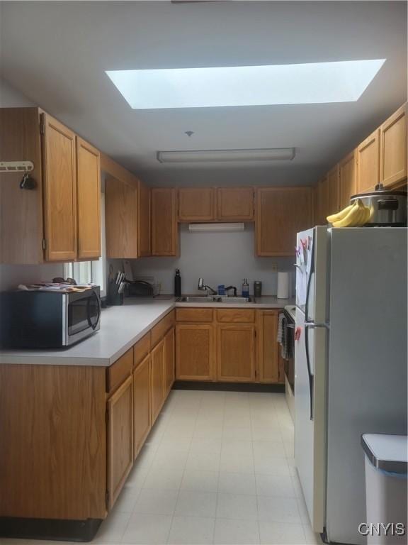 3903 Lafayette Rd, Lafayette, NY 13078 - kitchen featuring freestanding refrigerator, stainless steel microwave, a skylight, and light countertops