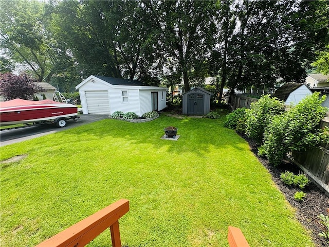 216 W William St Unit 201, Corning-City, NY 14830 - view of yard with a detached garage, a fire pit, a storage unit, and asphalt driveway