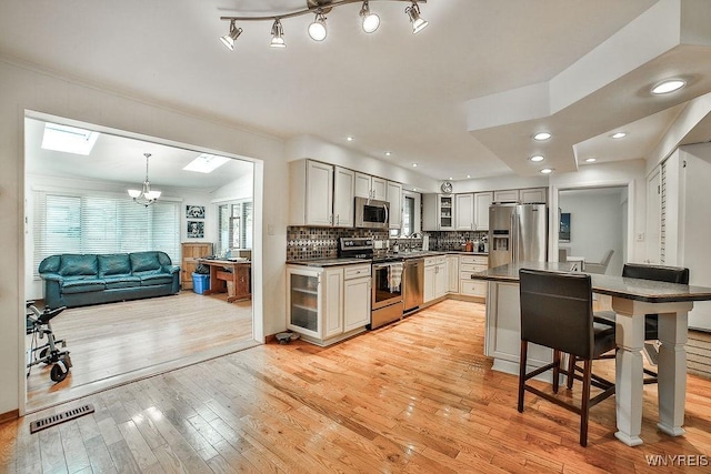 425 Vanderbilt Ave, Niagara Falls, NY 14305 - kitchen with appliances with stainless steel finishes, dark countertops, light wood-type flooring, glass insert cabinets, and a skylight