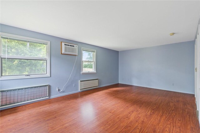 130 Quay Dr, Irondequoit, NY 14617 - spare room featuring radiator heating unit, wood finished floors, a wall unit AC, and a smoke detector