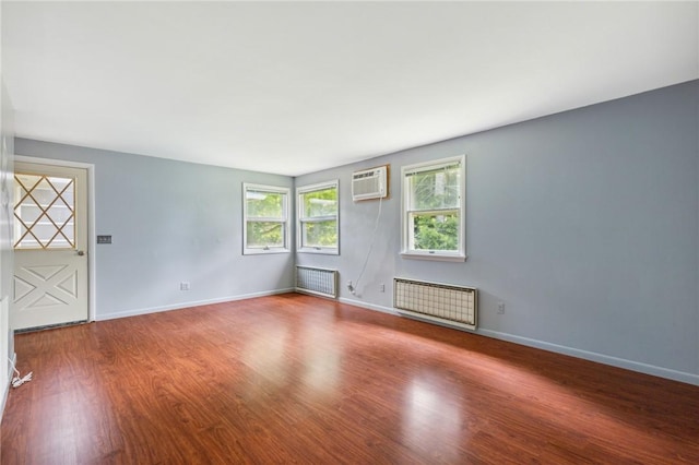 130 Quay Dr, Irondequoit, NY 14617 - empty room with radiator, wood finished floors, and a wall unit AC