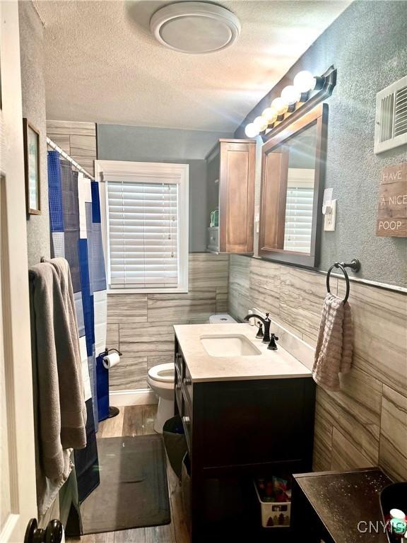 407 Pleasant St, Utica, NY 13501 - bathroom with tile walls, a textured ceiling, vanity, a shower with curtain, and a wainscoted wall
