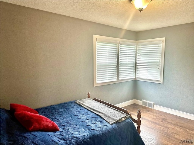 407 Pleasant St, Utica, NY 13501 - bedroom with wood finished floors, a textured wall, and a textured ceiling