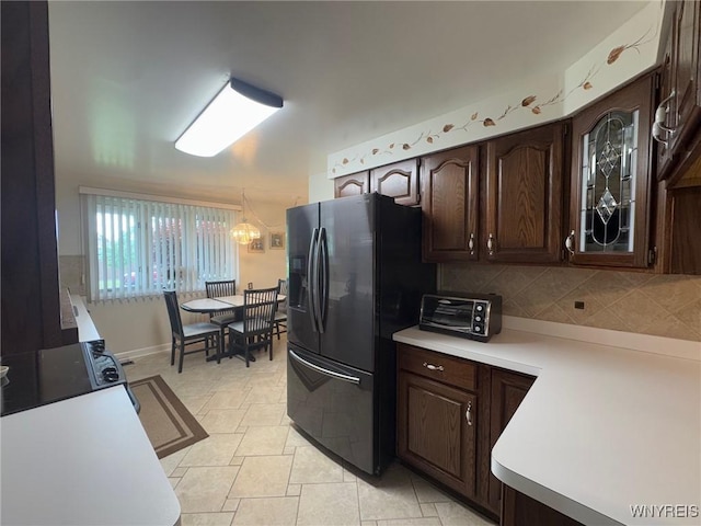 66 Fairlane Ave, Tonawanda-Town, NY 14150 - kitchen featuring black fridge, light countertops, dark brown cabinets, decorative backsplash, and a chandelier