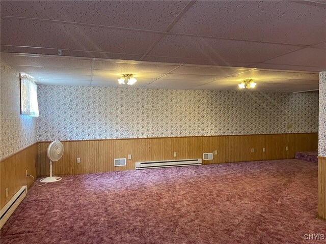 201 Sayles St, Oneida-Inside, NY 13421 - basement featuring baseboard heating, a baseboard heating unit, a paneled ceiling, a wainscoted wall, and carpet floors
