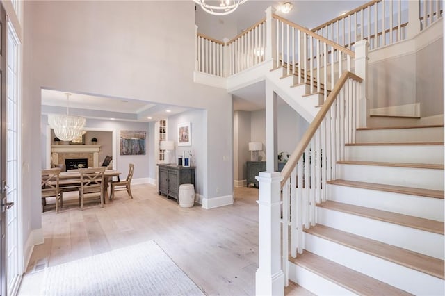 15 Cathedral Oaks, Perinton, NY 14450 - foyer featuring a towering ceiling, stairs, a fireplace, a chandelier, and light wood-type flooring