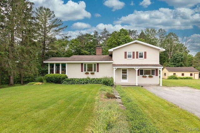 4581 Nelson Rd, Fenner, NY 13035 - view of front of house featuring a front yard, covered porch, asphalt driveway, a chimney, and view of wooded area