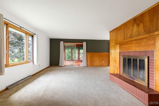 4581 Nelson Rd, Fenner, NY 13035 - unfurnished living room featuring baseboard heating, a brick fireplace, healthy amount of natural light, carpet floors, and wood walls