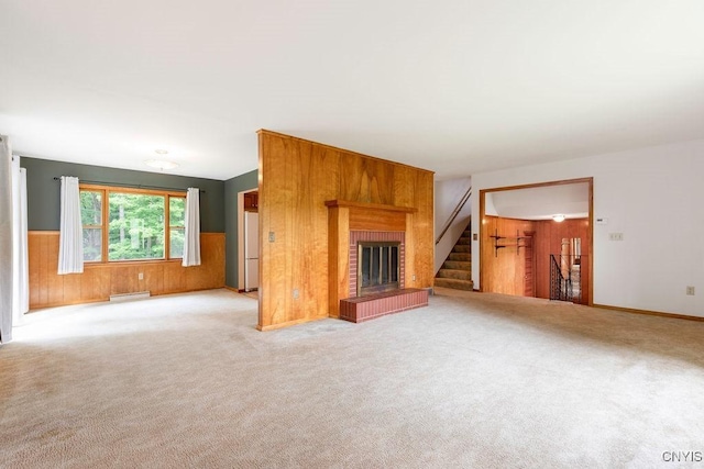 4581 Nelson Rd, Fenner, NY 13035 - unfurnished living room featuring wooden walls, stairway, carpet, wainscoting, and a brick fireplace