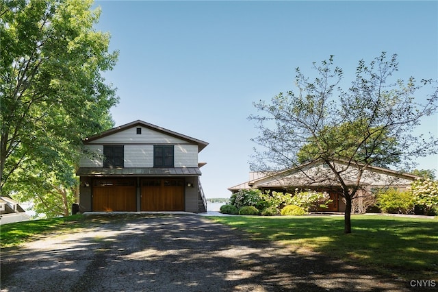 23986 Smith Rd, Alexandria, NY 13607 - view of front facade with a garage, gravel driveway, a front yard, and a metal roof