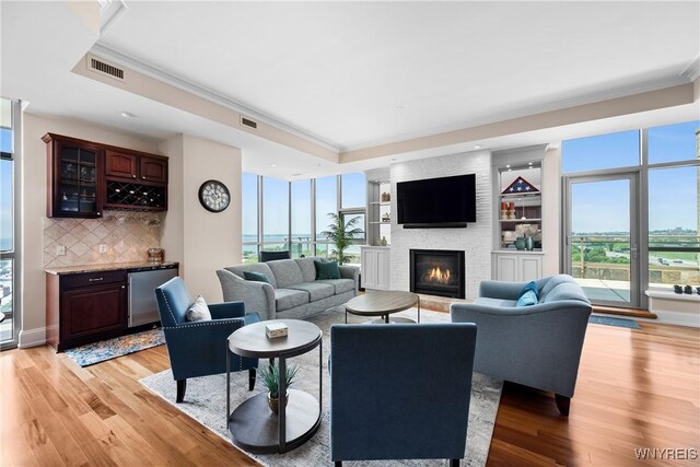 132 Lakefront Blvd Unit 804, Buffalo, NY 14202 - living area featuring a raised ceiling, crown molding, wet bar, light wood-style floors, and a large fireplace