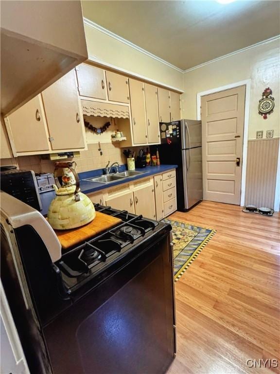 373 S Collingwood Ave, Syracuse, NY 13206 - kitchen with black gas range oven, freestanding refrigerator, crown molding, light wood-style floors, and dark countertops