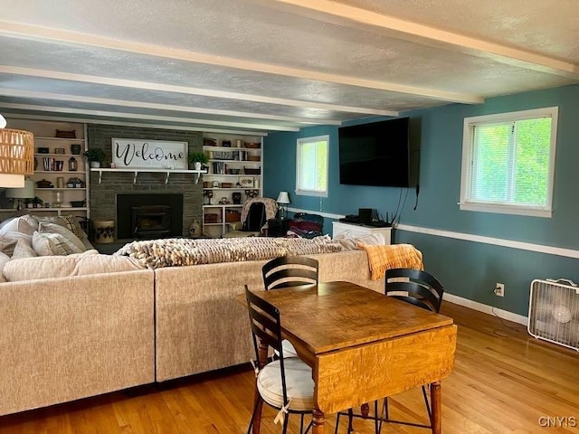 60 Cambridge Rd, Whitestown, NY 13492 - living room featuring beamed ceiling, wood finished floors, a fireplace, a textured ceiling, and built in shelves