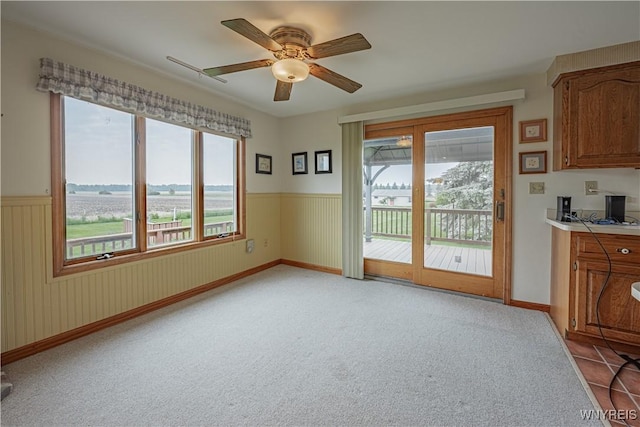 4724 Wilson Burt Rd, Wilson, NY 14172 - unfurnished dining area featuring a ceiling fan, a wainscoted wall, and light colored carpet