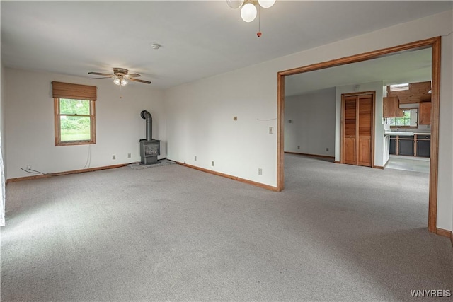 4724 Wilson Burt Rd, Wilson, NY 14172 - unfurnished living room featuring a wood stove, a ceiling fan, plenty of natural light, and carpet
