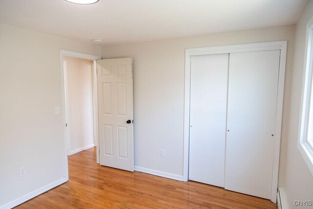 4114 Wetzel Rd, Clay, NY 13090 - unfurnished bedroom featuring light wood-style flooring, a baseboard heating unit, and a closet