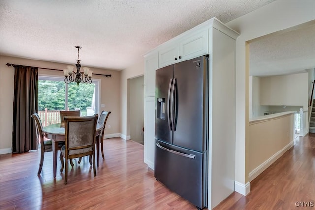 40 Phyllis Ln, Hastings, NY 13076 - dining room featuring a textured ceiling, a chandelier, light wood-type flooring, and stairway