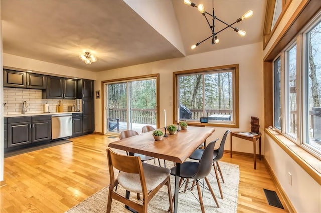 735 Howell Rd, Conquest, NY 13140 - dining area featuring light wood-type flooring, a chandelier, and vaulted ceiling