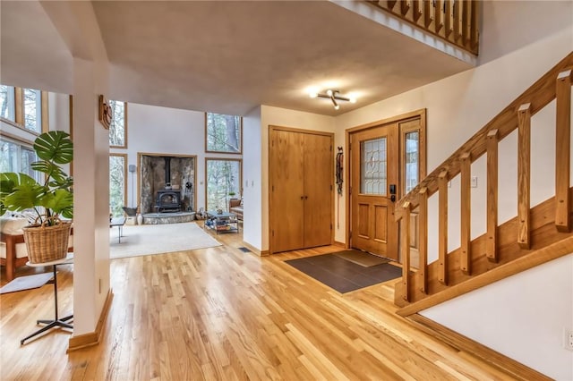 735 Howell Rd, Conquest, NY 13140 - foyer featuring healthy amount of natural light, light wood finished floors, a wood stove, and stairs