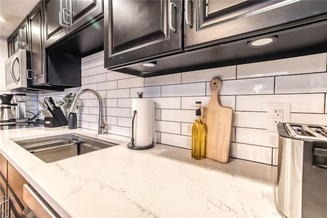 735 Howell Rd, Conquest, NY 13140 - kitchen with tasteful backsplash, stainless steel microwave, light stone counters, and dark cabinetry