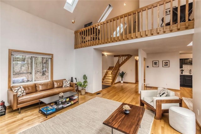 735 Howell Rd, Conquest, NY 13140 - living room with high vaulted ceiling, a skylight, stairs, and wood finished floors
