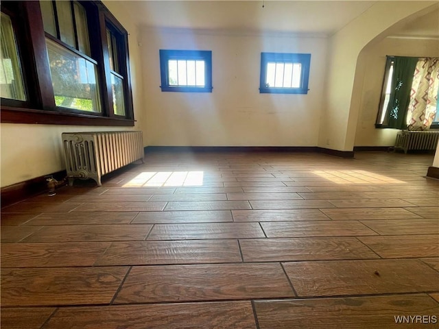 2010 Niagara St, Niagara Falls, NY 14303 - empty room with radiator heating unit, hardwood / wood-style flooring, arched walkways, and ornamental molding