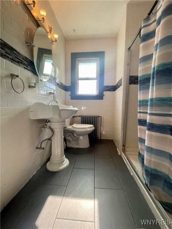 2010 Niagara St, Niagara Falls, NY 14303 - bathroom with radiator heating unit, tile walls, and shower / tub combo with curtain